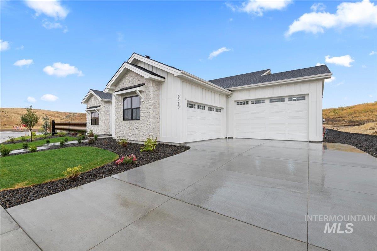 View of home's exterior featuring stone siding, board and batten siding, a garage, and driveway