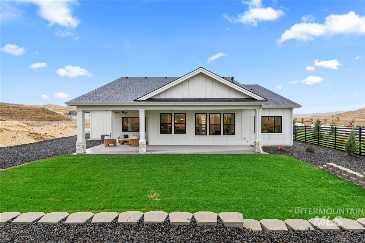 Back of house with board and batten siding, a fenced backyard, a patio, and a shingled roof