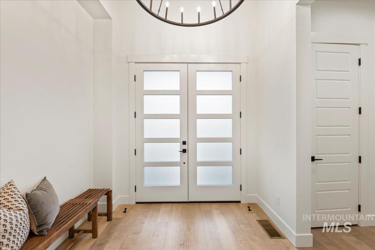 Doorway to outside with french doors, wood finished floors, and a chandelier