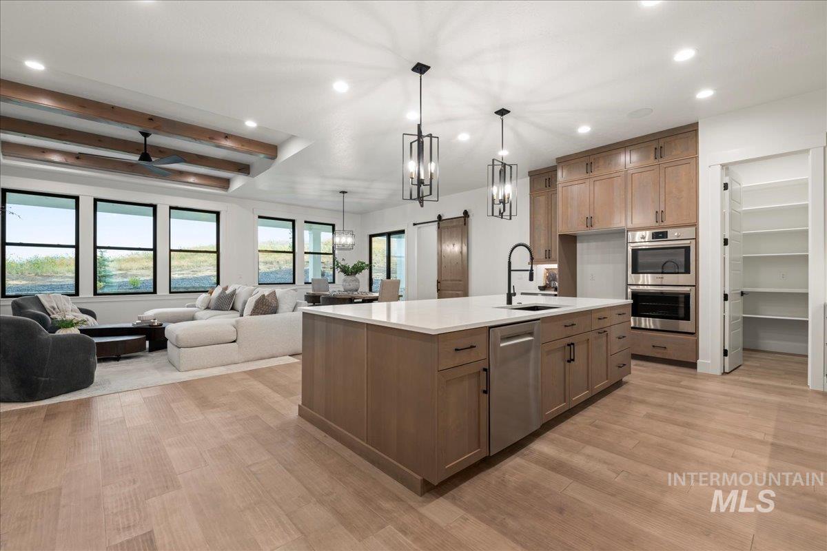 Kitchen with a barn door, recessed lighting, brown cabinetry, open floor plan, and pendant lighting