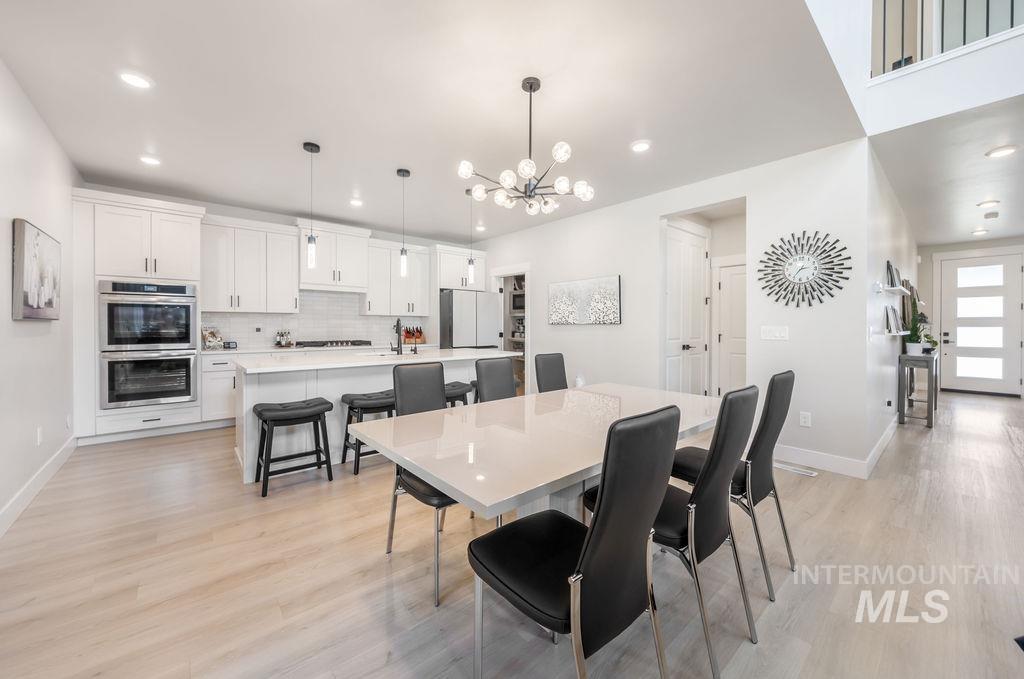 Dining space with a chandelier, light wood-style flooring, and recessed lighting