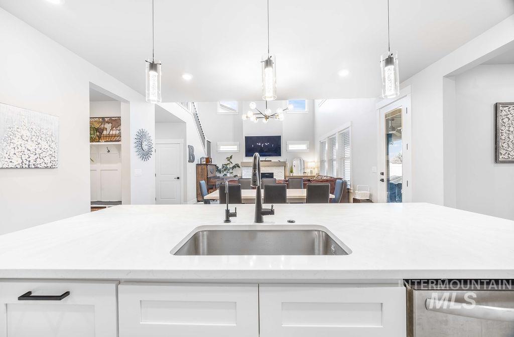 Kitchen featuring hanging light fixtures, white cabinets, light stone countertops, a chandelier, and open floor plan