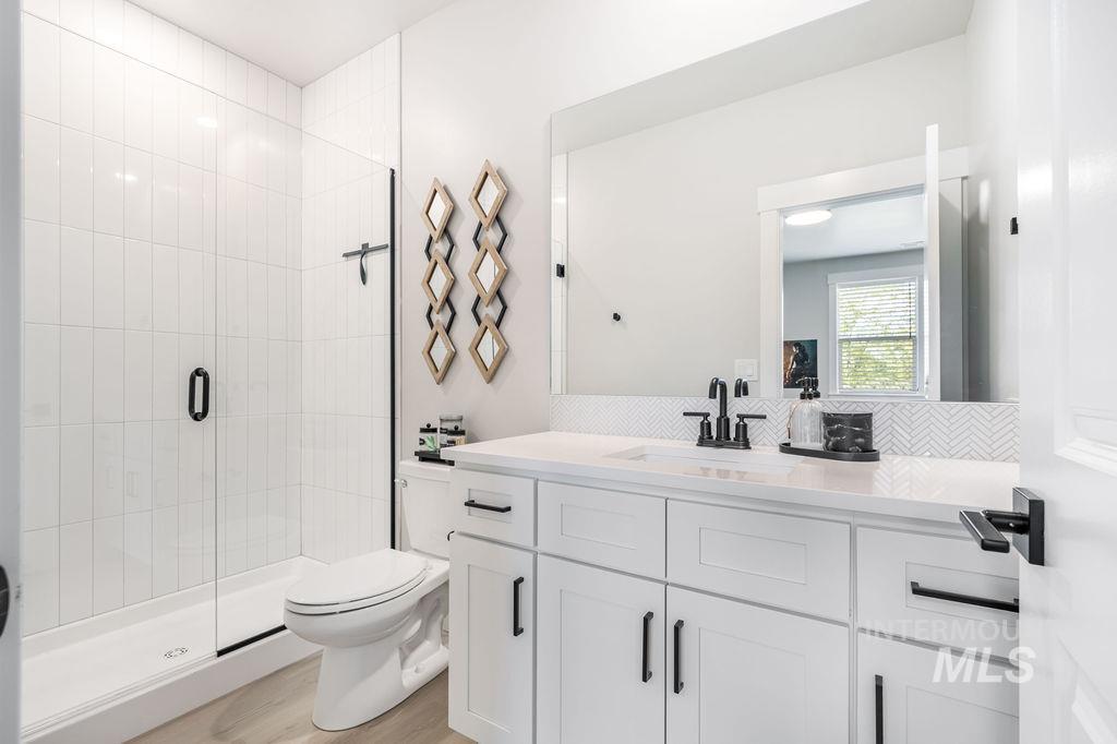 Full bath featuring a shower stall, vanity, and light wood-style floors
