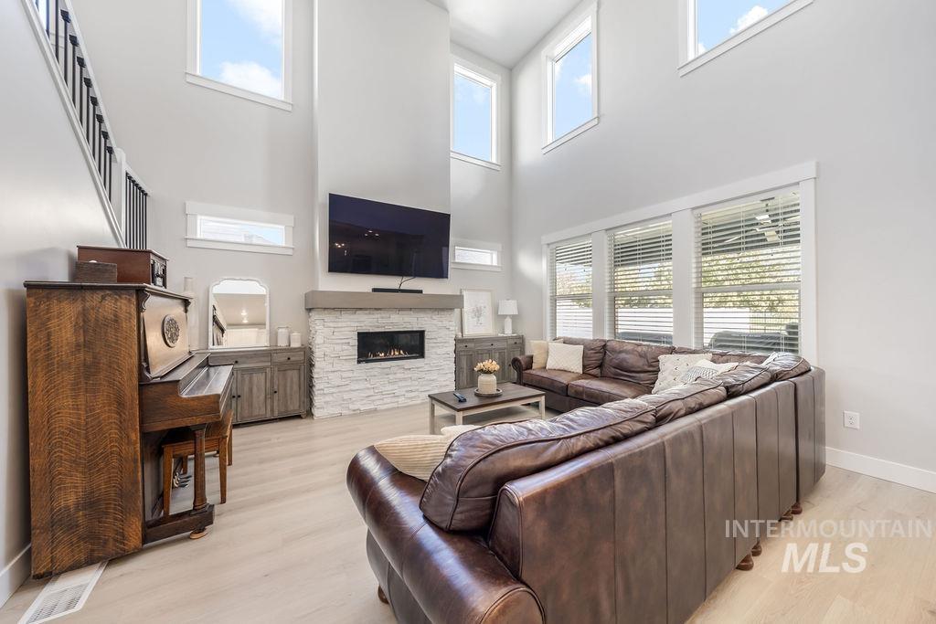 Living area featuring light wood-style floors, a high ceiling, and a stone fireplace