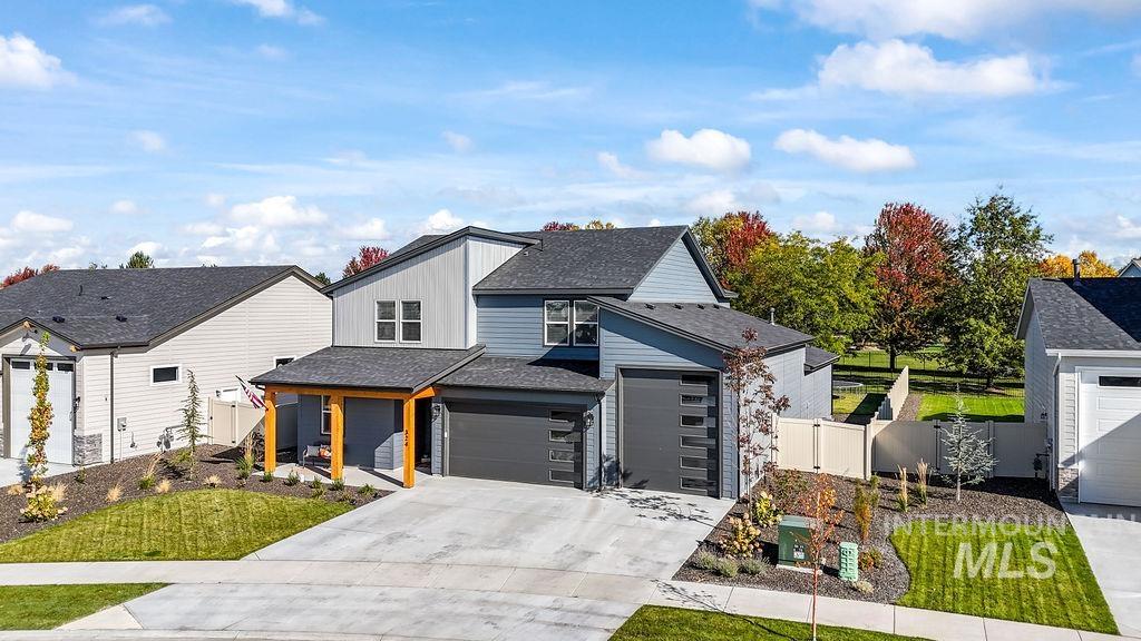 View of front of house with roof with shingles, concrete driveway, board and batten siding, and a gate
