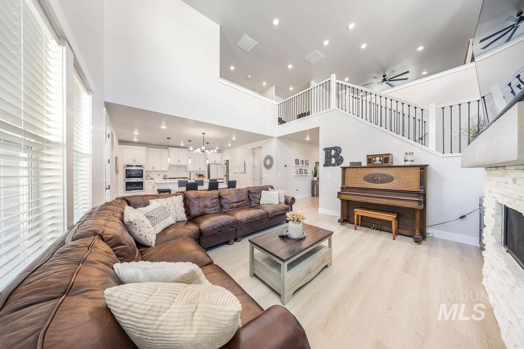 Living area featuring a chandelier, recessed lighting, light wood-style flooring, ceiling fan, and a high ceiling