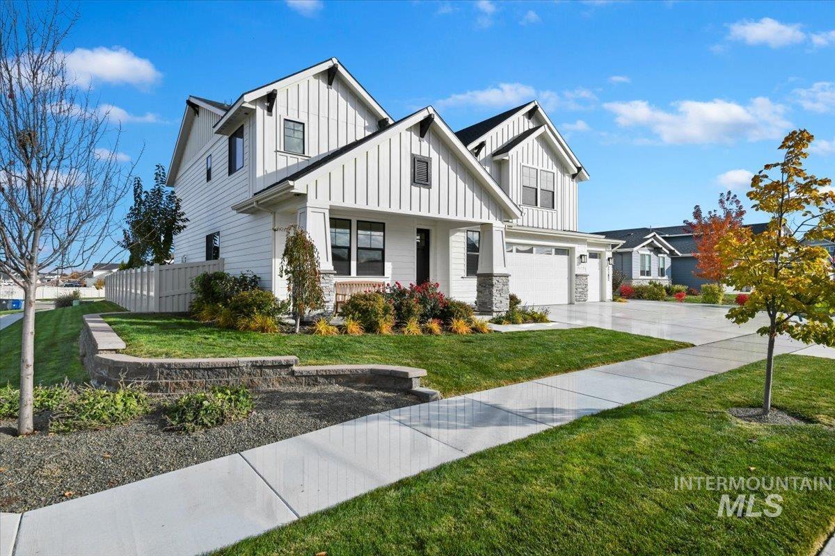 Modern farmhouse style home featuring an attached garage, concrete driveway, board and batten siding, a porch, and stone siding