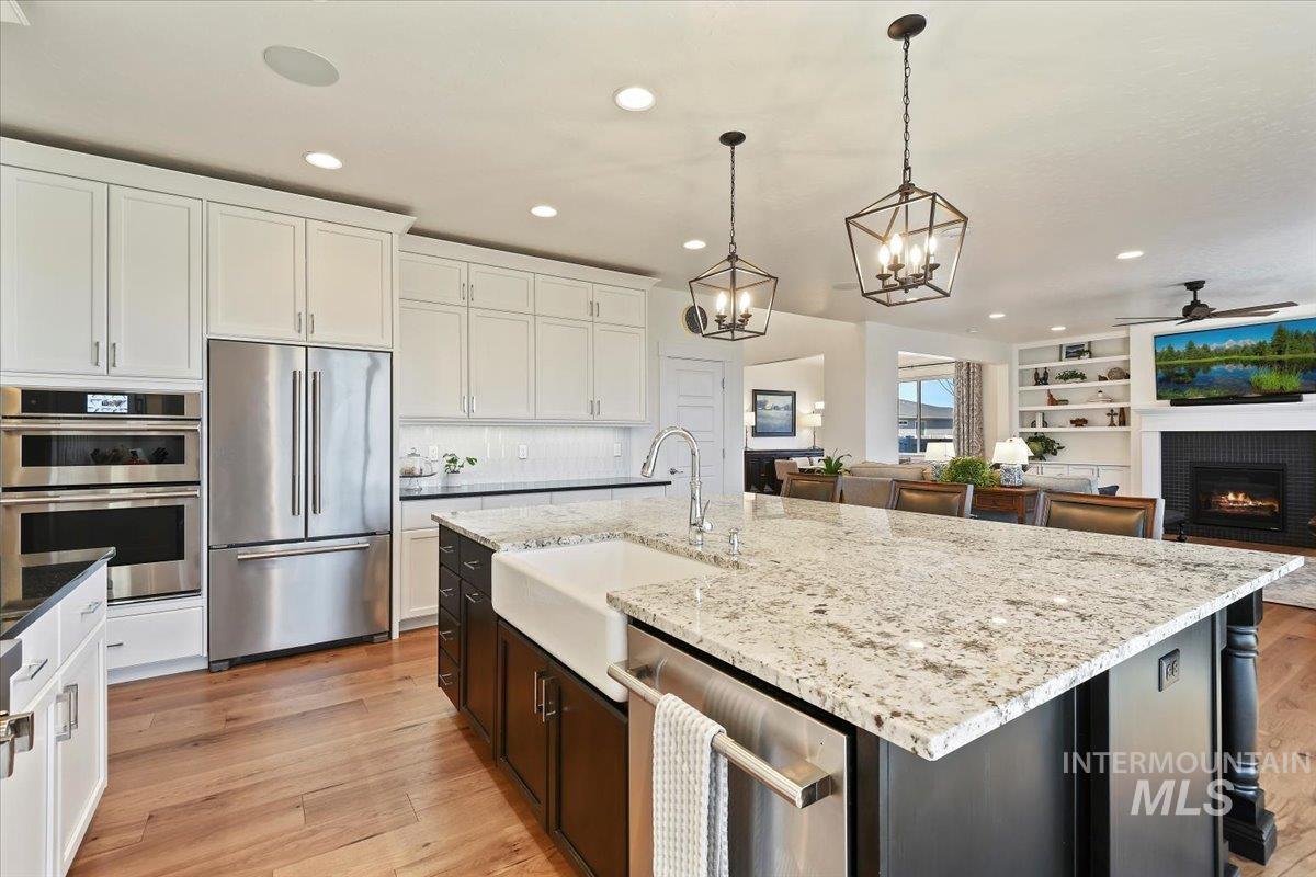 Kitchen with stainless steel appliances, white cabinets, hanging light fixtures, light wood-type flooring, and recessed lighting