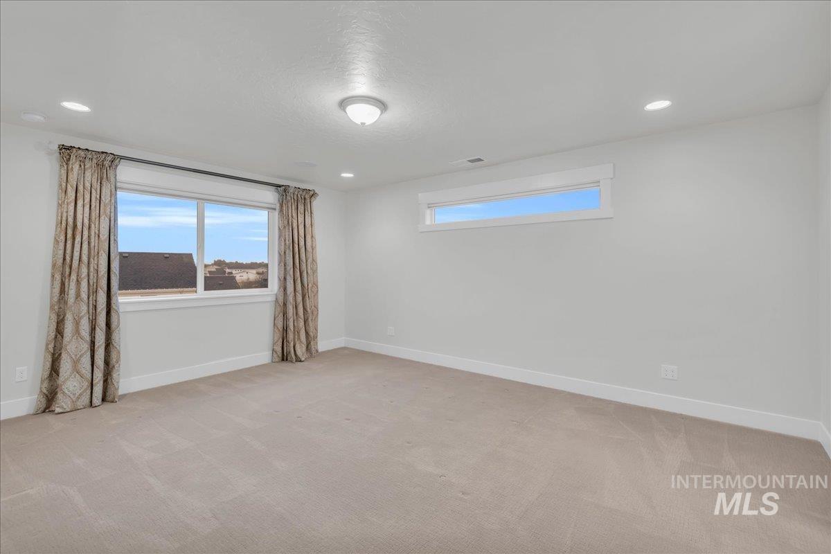 Spare room featuring recessed lighting, plenty of natural light, light carpet, and a textured ceiling
