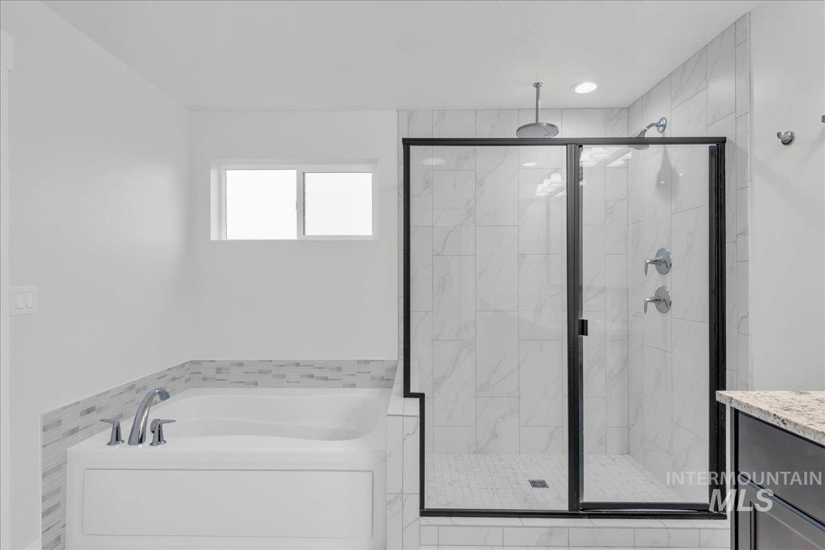 Bathroom featuring vanity, a bath, and a marble finish shower