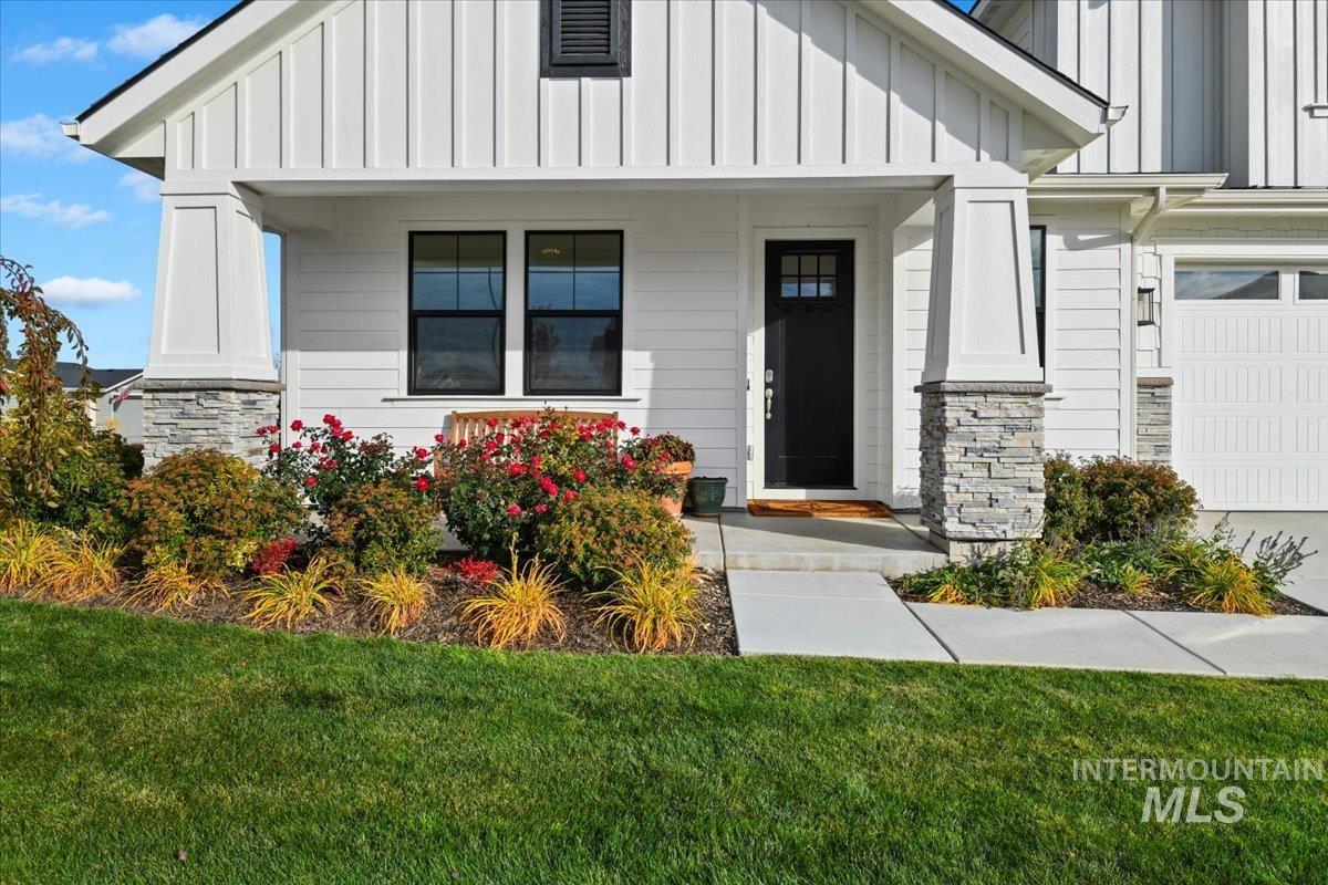 Property entrance with board and batten siding, stone siding, a yard, and a garage