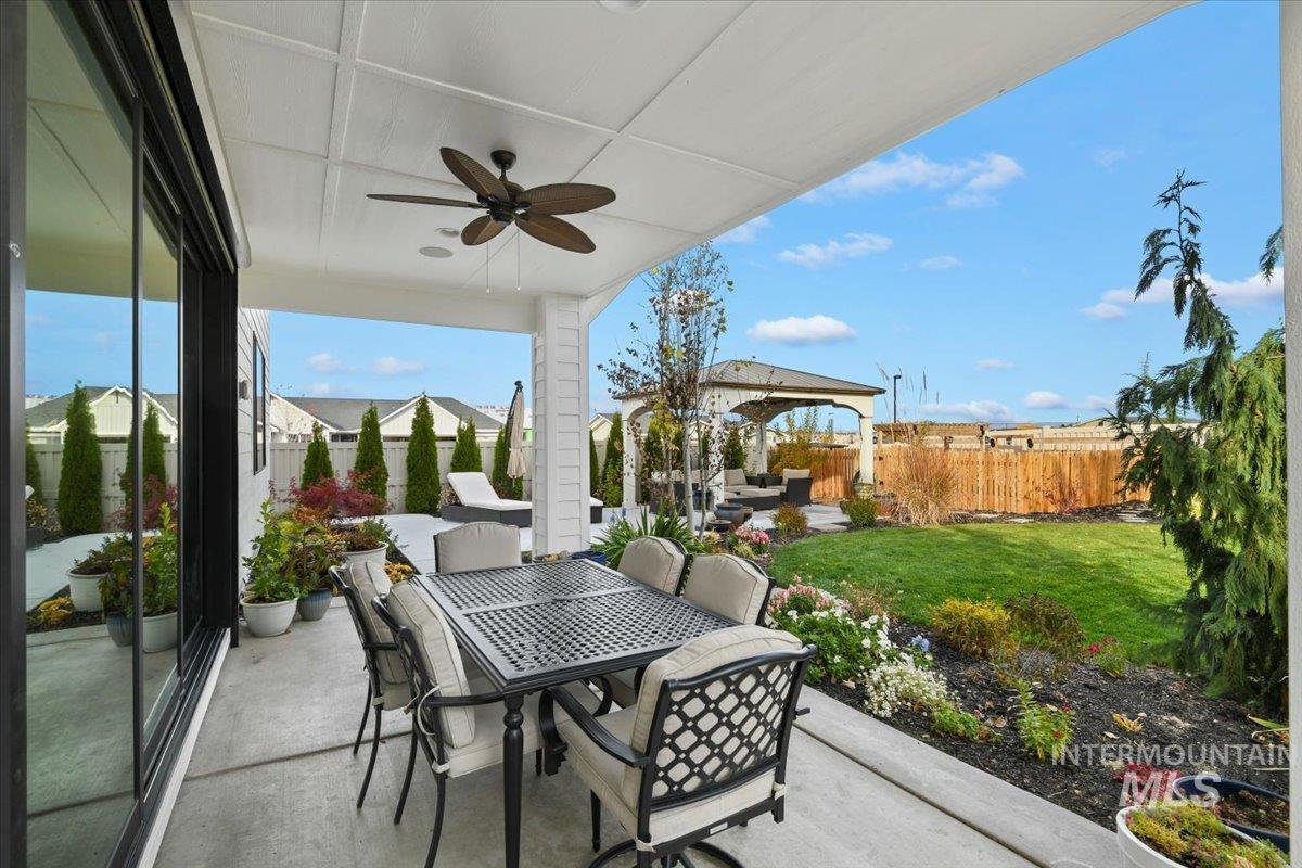 Fenced backyard featuring ceiling fan, a patio area, and outdoor dining area