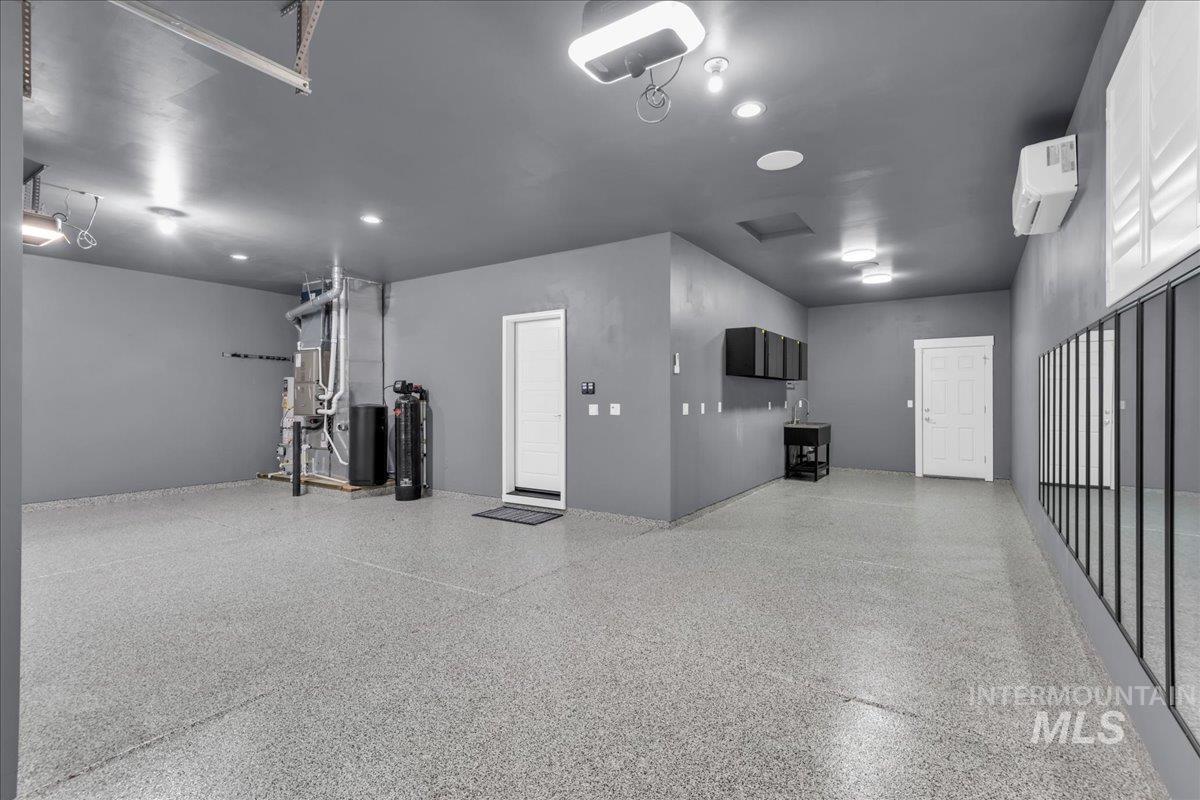 Garage with heating unit, a garage door opener, a wall mounted AC, and recessed lighting