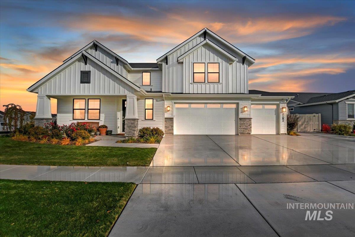 View of front of house with a yard, board and batten siding, driveway, and stone siding