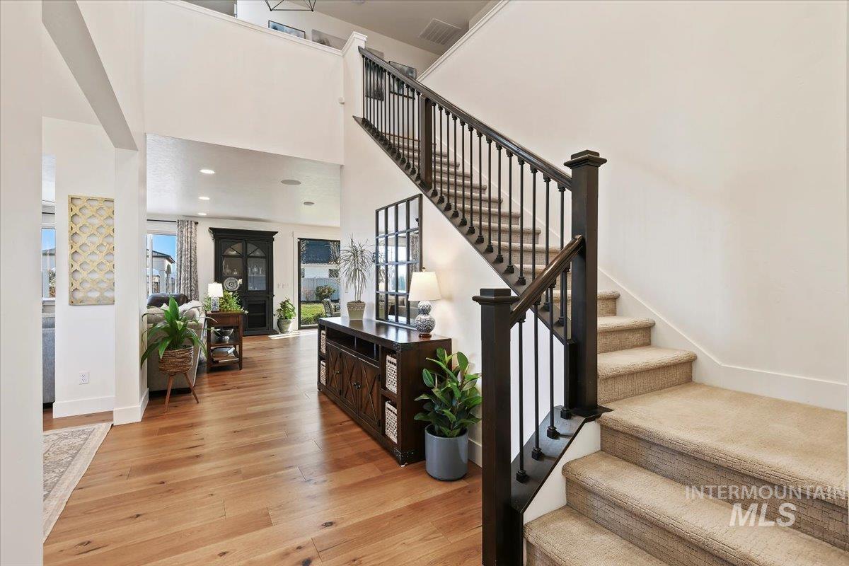 Stairs with hardwood / wood-style flooring and a towering ceiling