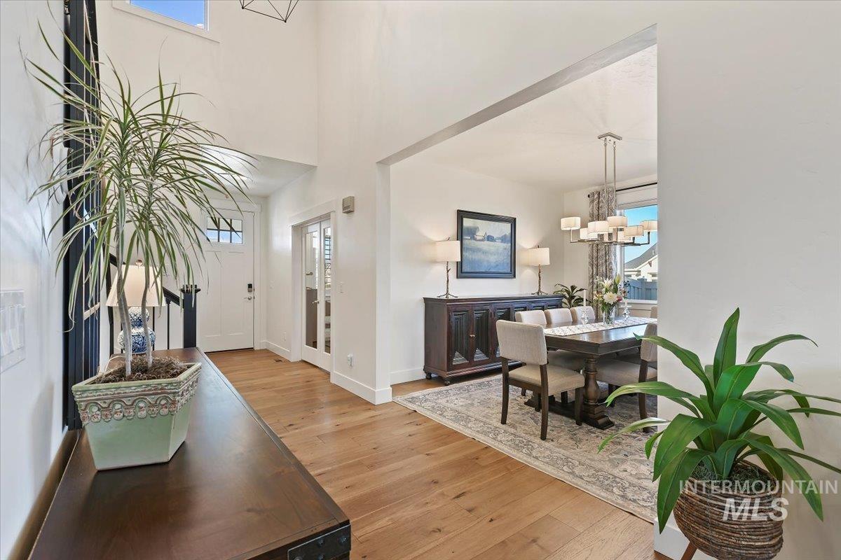 Entryway with light wood-style flooring, a chandelier, and a high ceiling