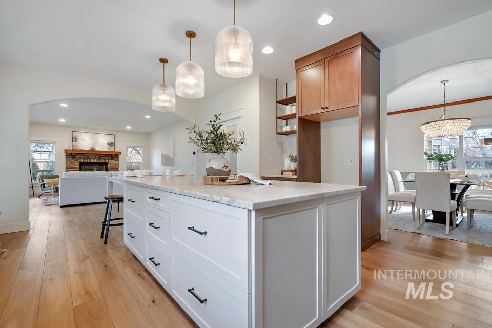 Kitchen featuring arched walkways, open floor plan, light wood-style floors, pendant lighting, and recessed lighting