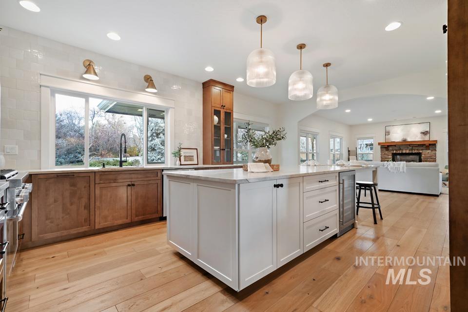 Kitchen with white cabinetry, a center island, decorative light fixtures, a kitchen breakfast bar, and stainless steel range