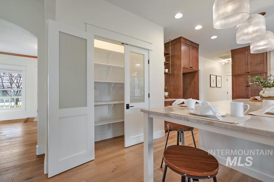 Kitchen featuring brown cabinetry, light wood-style flooring, a breakfast bar area, pendant lighting, and recessed lighting