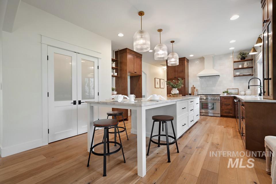 Kitchen with open shelves, white cabinets, decorative light fixtures, stainless steel range, and recessed lighting
