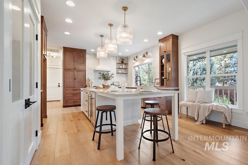 Kitchen featuring brown cabinetry, open shelves, a breakfast bar, hanging light fixtures, and recessed lighting
