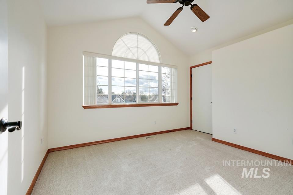 Spare room with lofted ceiling, light carpet, and ceiling fan