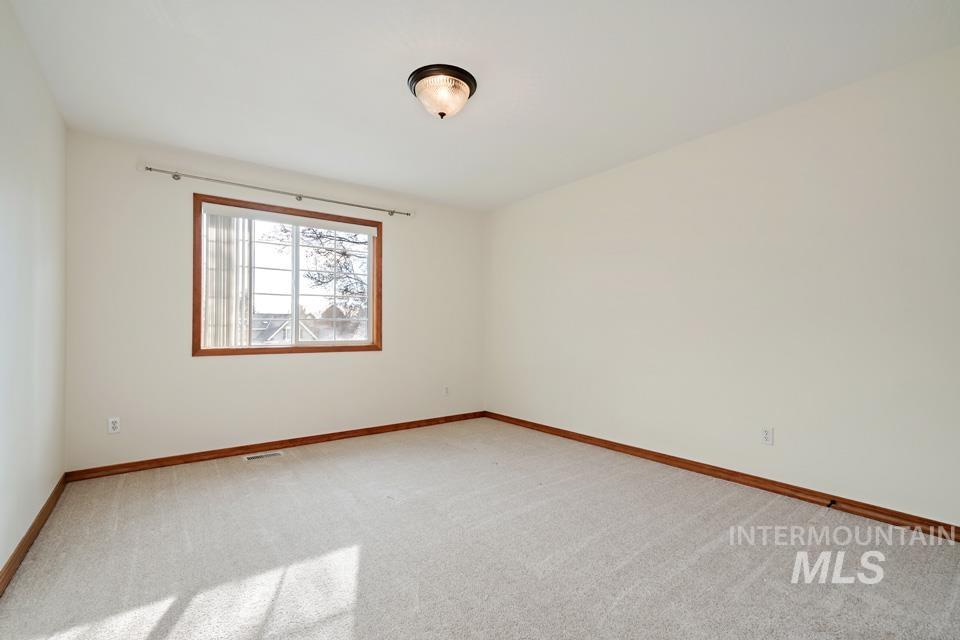 Spare room featuring light carpet and baseboards