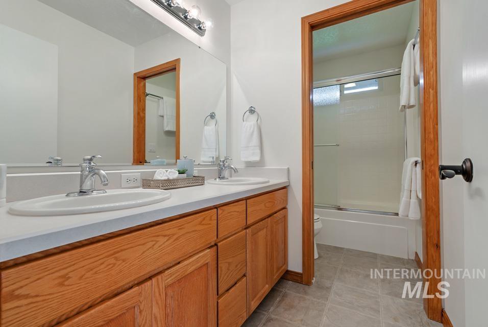 Bathroom with double vanity and combined bath / shower with glass door