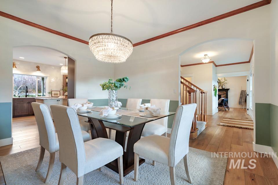 Dining room with arched walkways, crown molding, hardwood / wood-style floors, a chandelier, and a fireplace