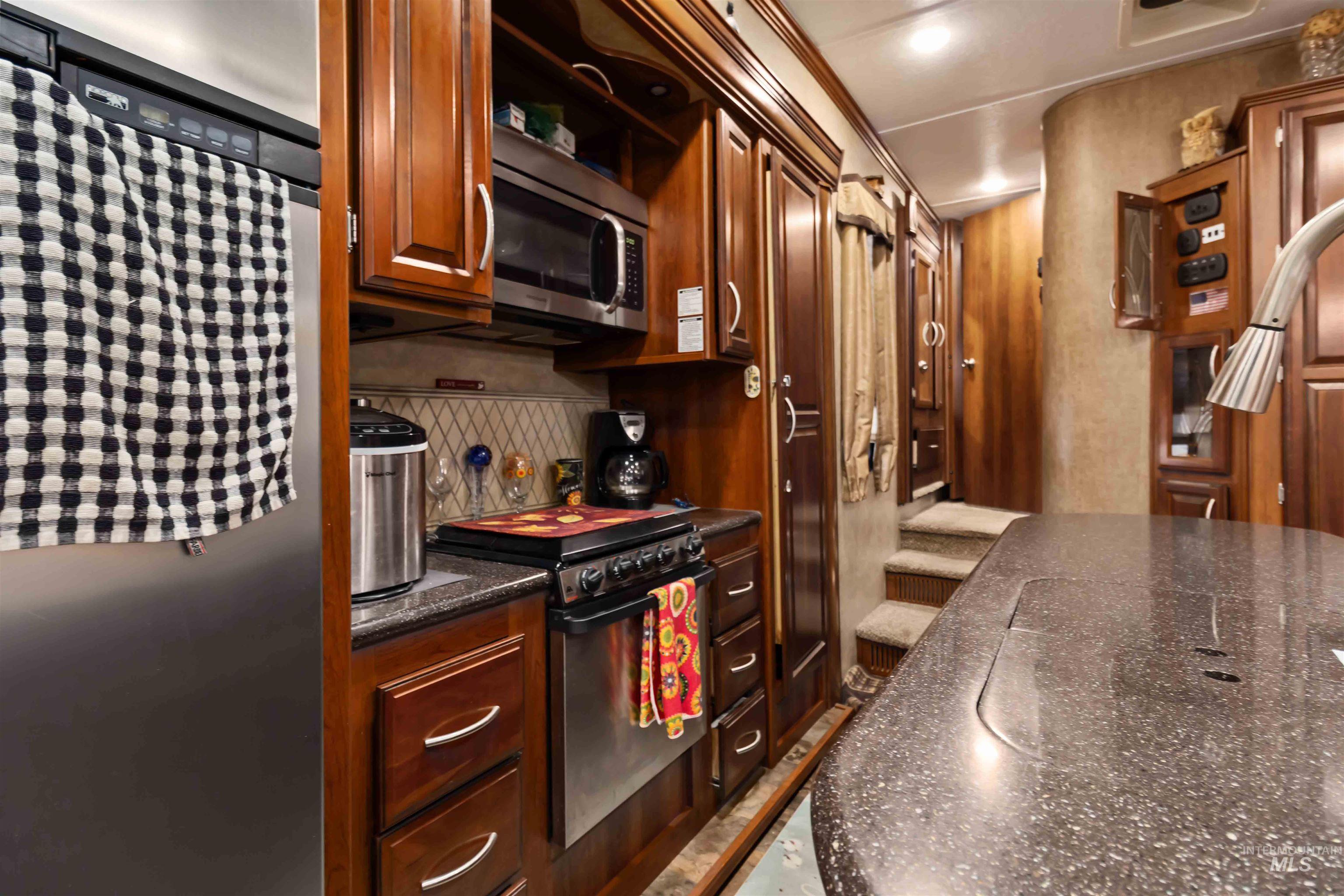 Kitchen with stainless steel appliances, dark stone counters, tasteful backsplash, and open shelves