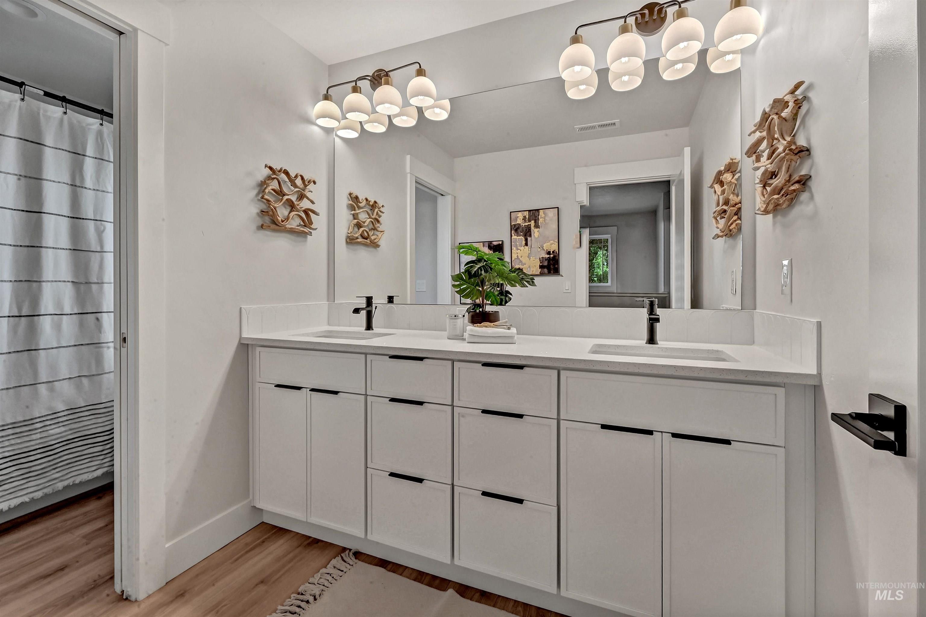 Full bath featuring double vanity and light wood-type flooring