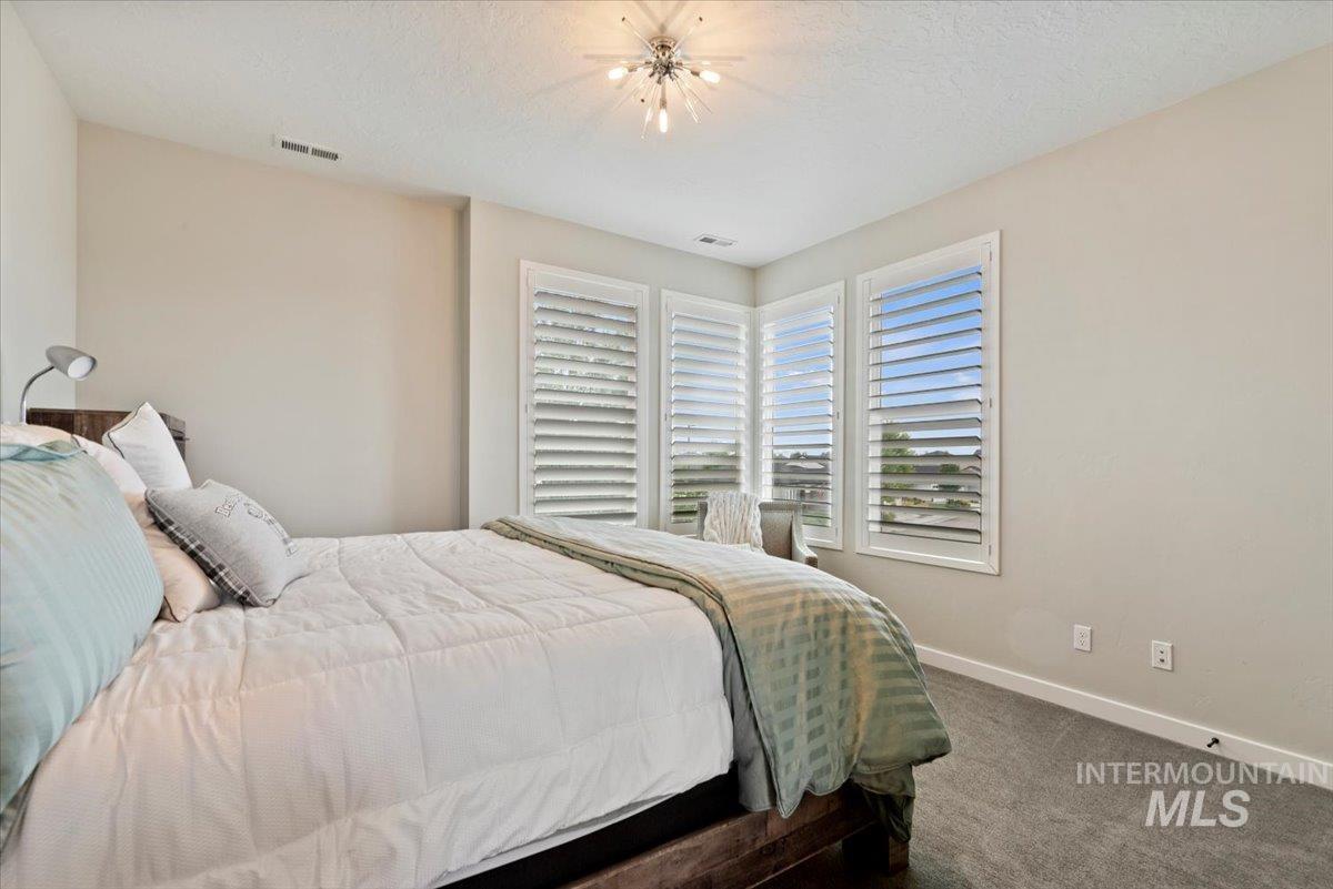 Bedroom with carpet floors, a textured ceiling, and a chandelier