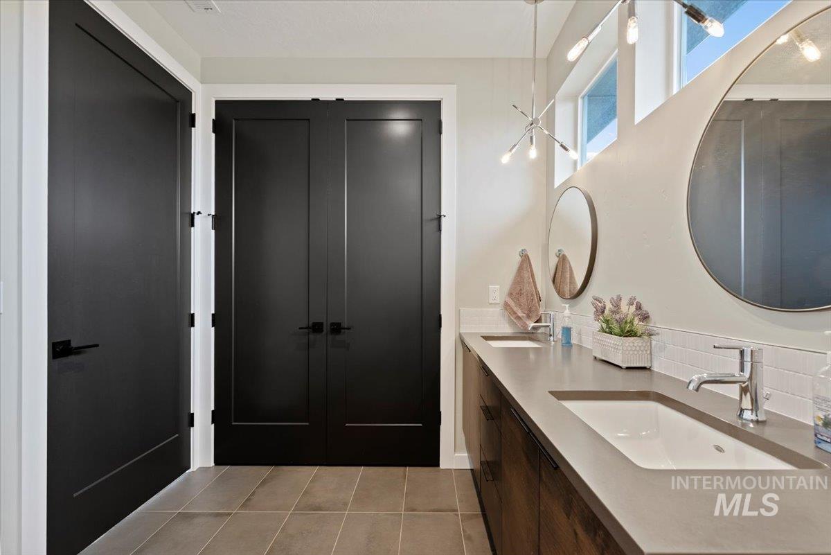 Full bath with light tile patterned floors, double vanity, and tasteful backsplash