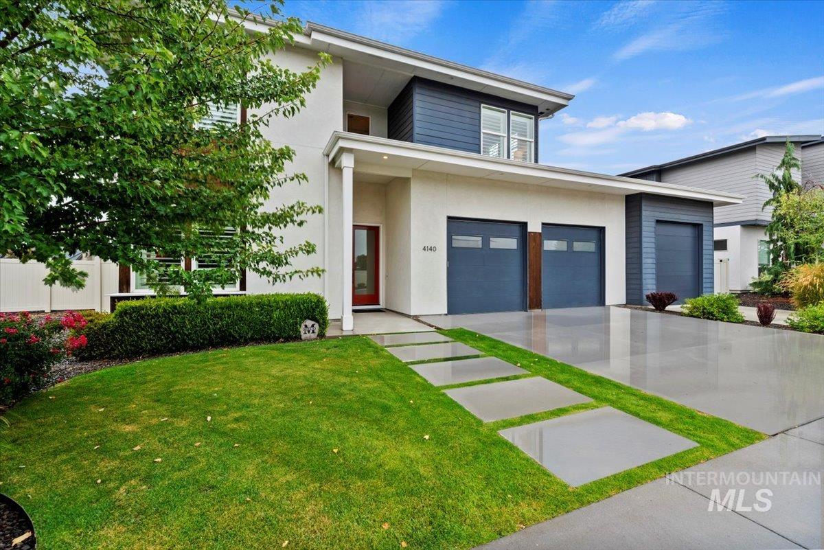 Contemporary house featuring a front lawn, concrete driveway, and stucco siding