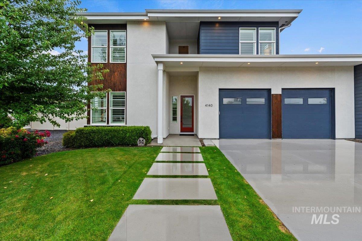Contemporary home featuring stucco siding, a front lawn, a garage, and concrete driveway