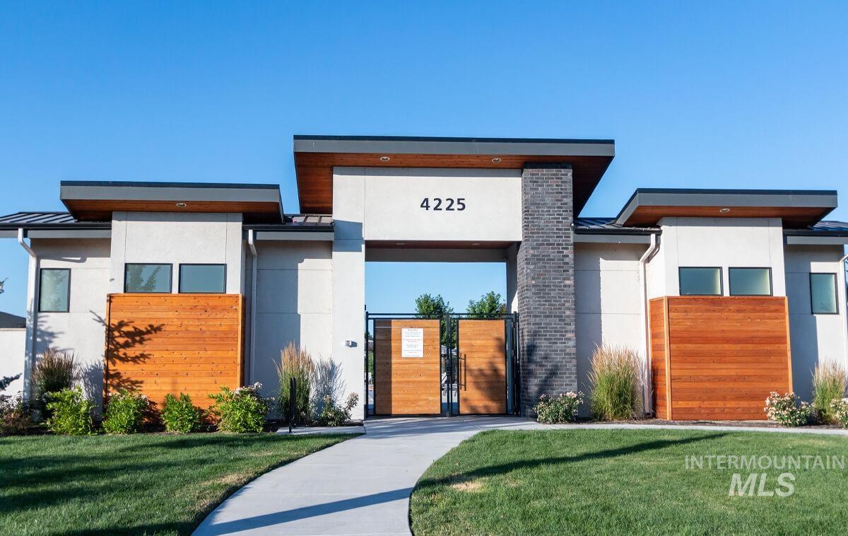 Contemporary house featuring stucco siding, a gate, a front yard, and a standing seam roof