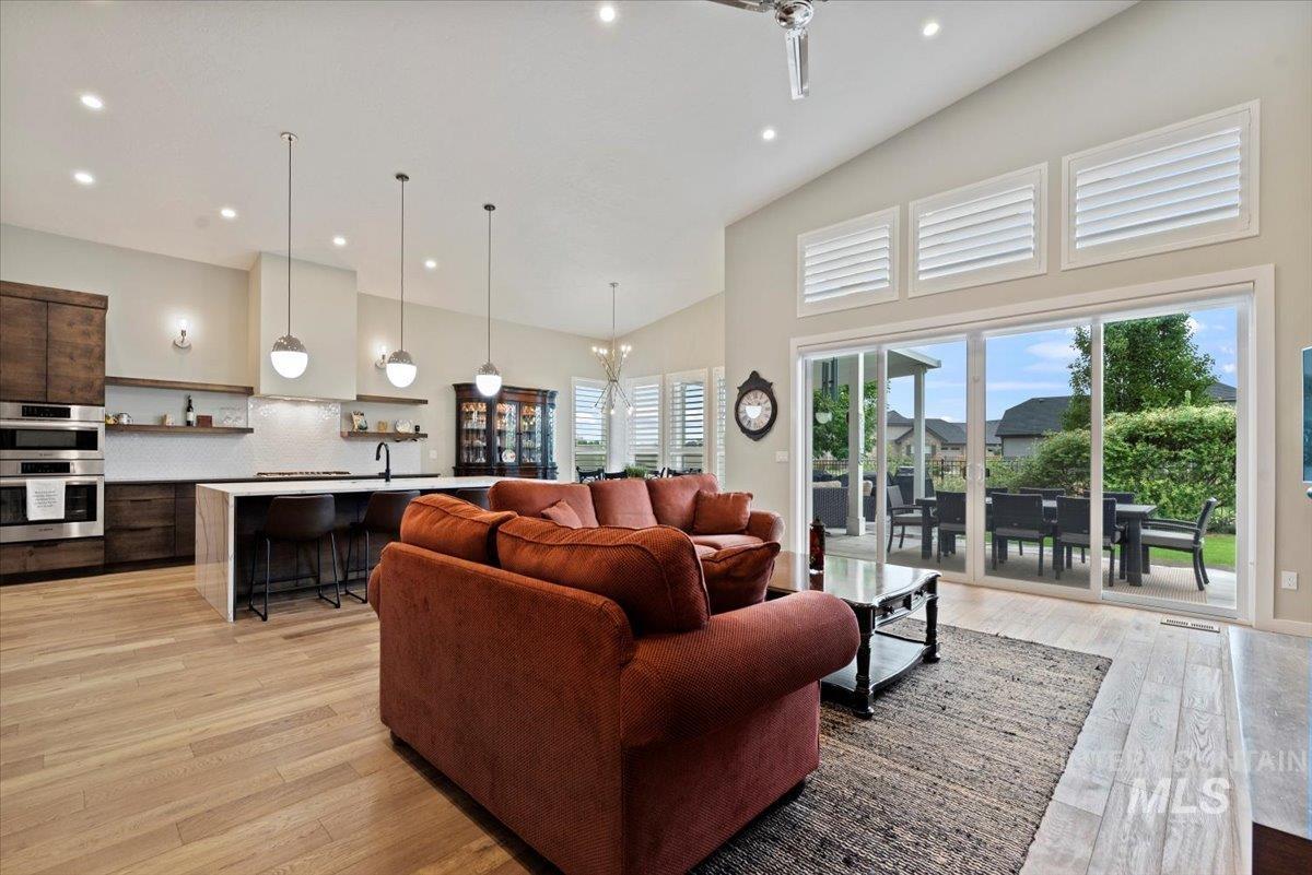 Living room with a chandelier, light wood-type flooring, recessed lighting, and high vaulted ceiling