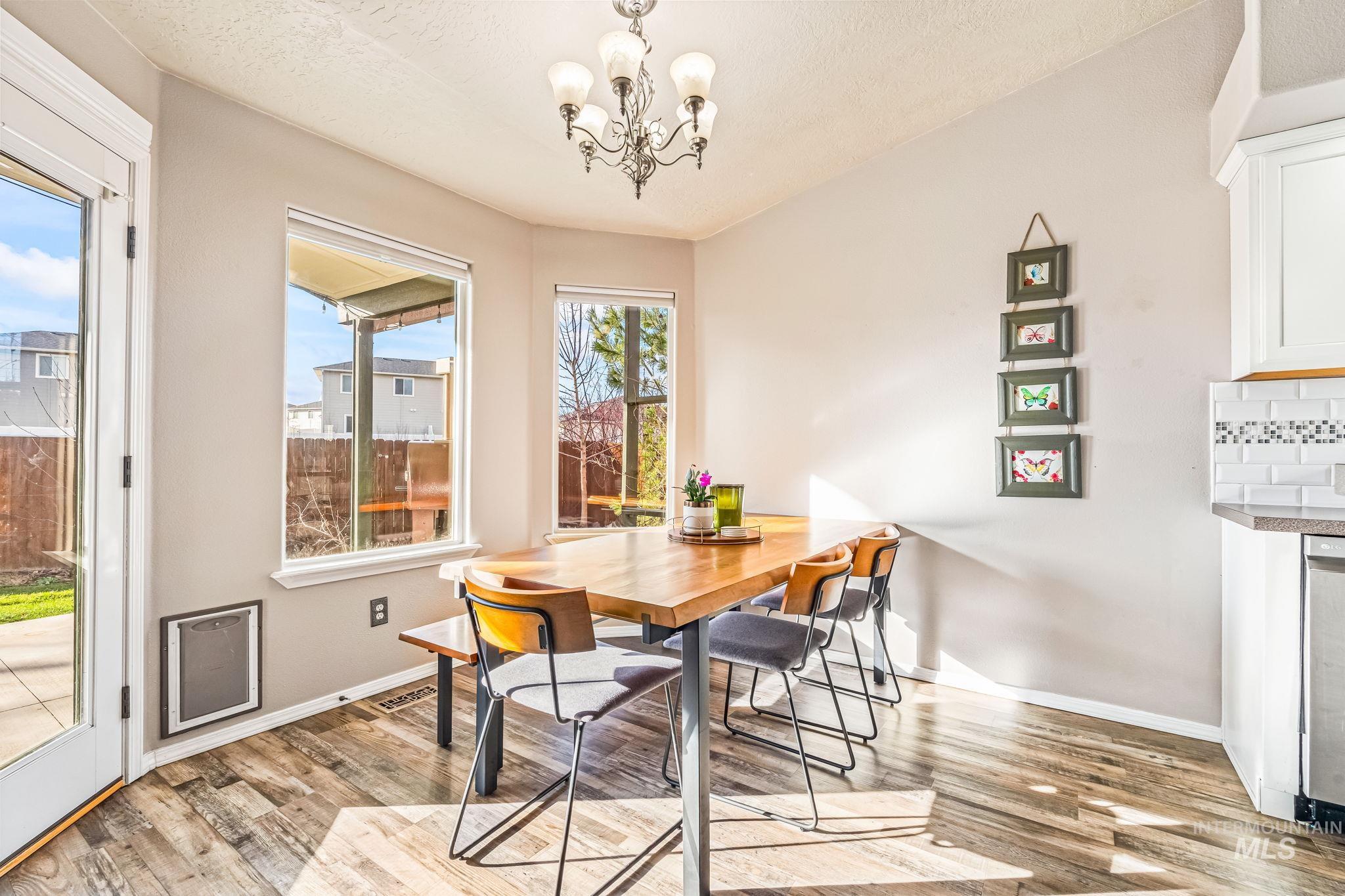 Dining space featuring a chandelier, light wood-type flooring, and a textured ceiling