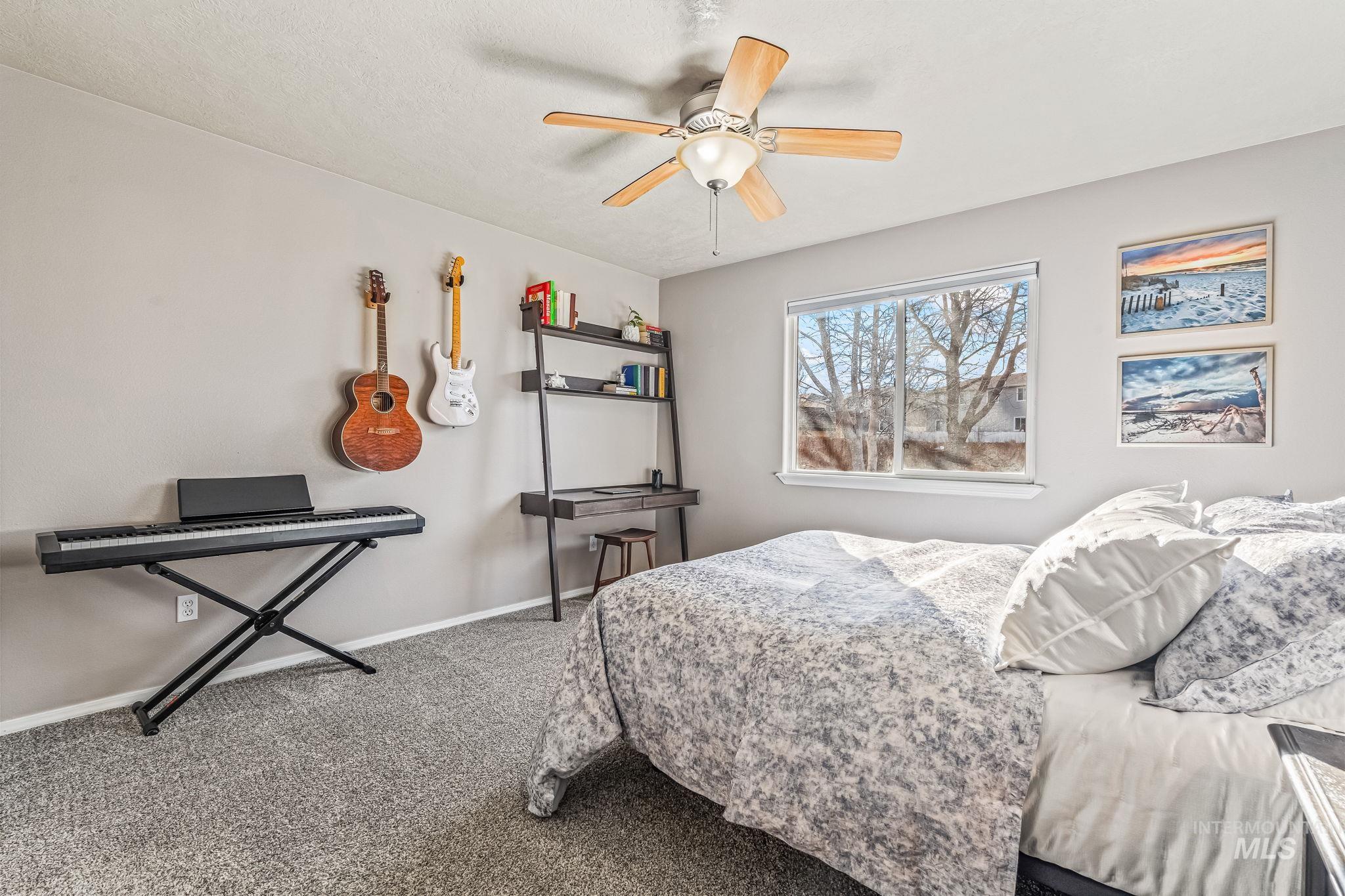 Carpeted bedroom featuring ceiling fan and baseboards