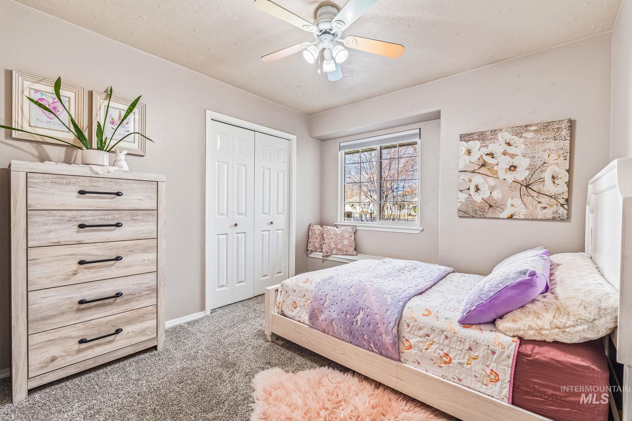 Bedroom with light colored carpet, a closet, and a ceiling fan