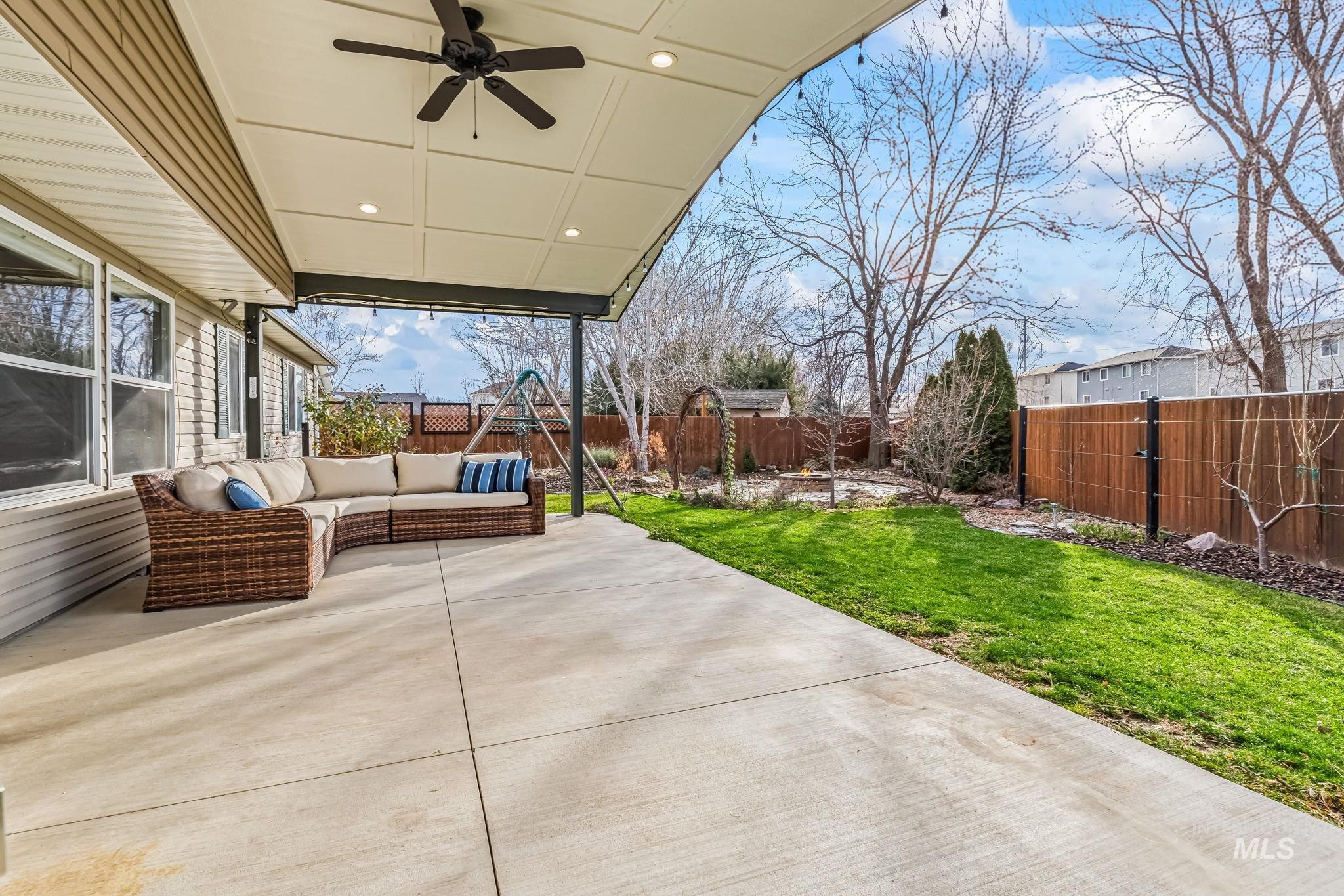 Fenced backyard with a patio area, an outdoor hangout area, and a ceiling fan