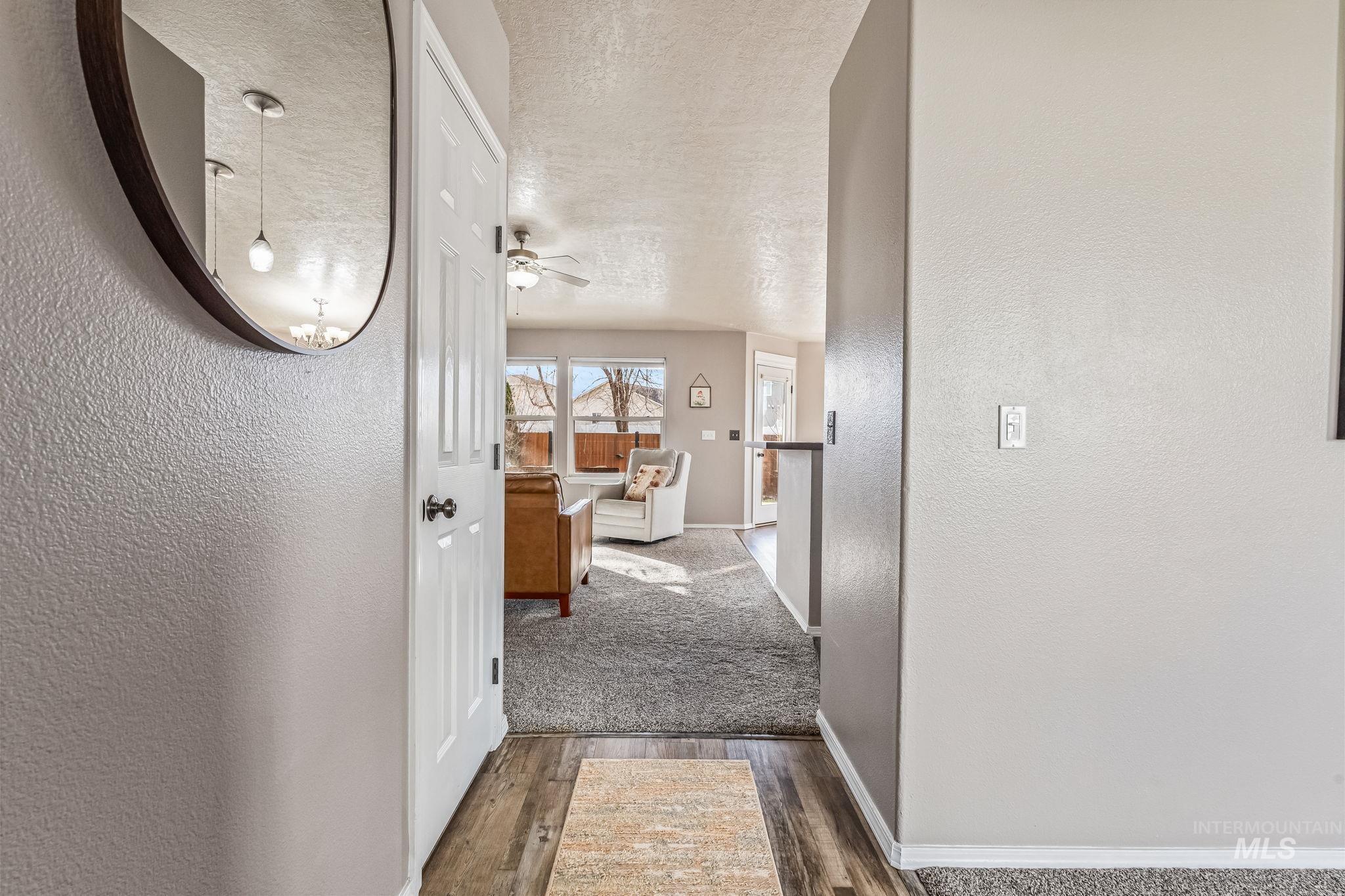 Corridor with a textured wall, a textured ceiling, and dark wood-style floors