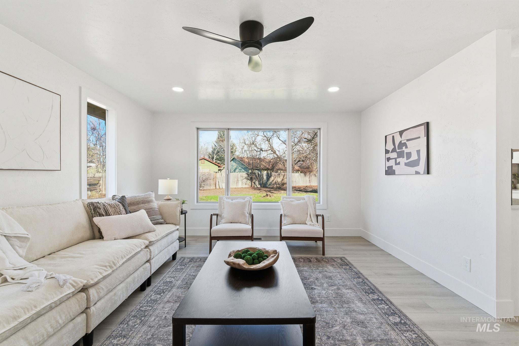 Living area featuring light wood-style floors, ceiling fan, and recessed lighting