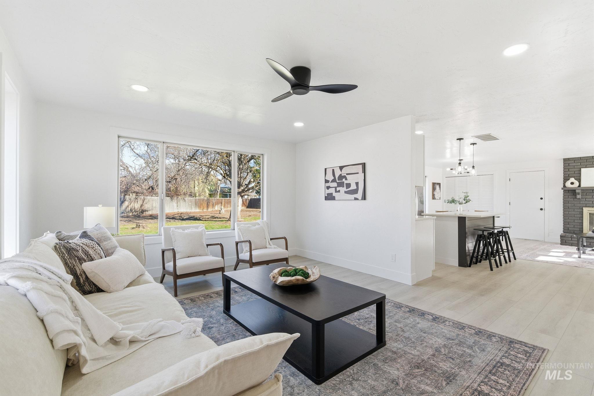 Living room with a ceiling fan, light wood-style flooring, recessed lighting, and a fireplace