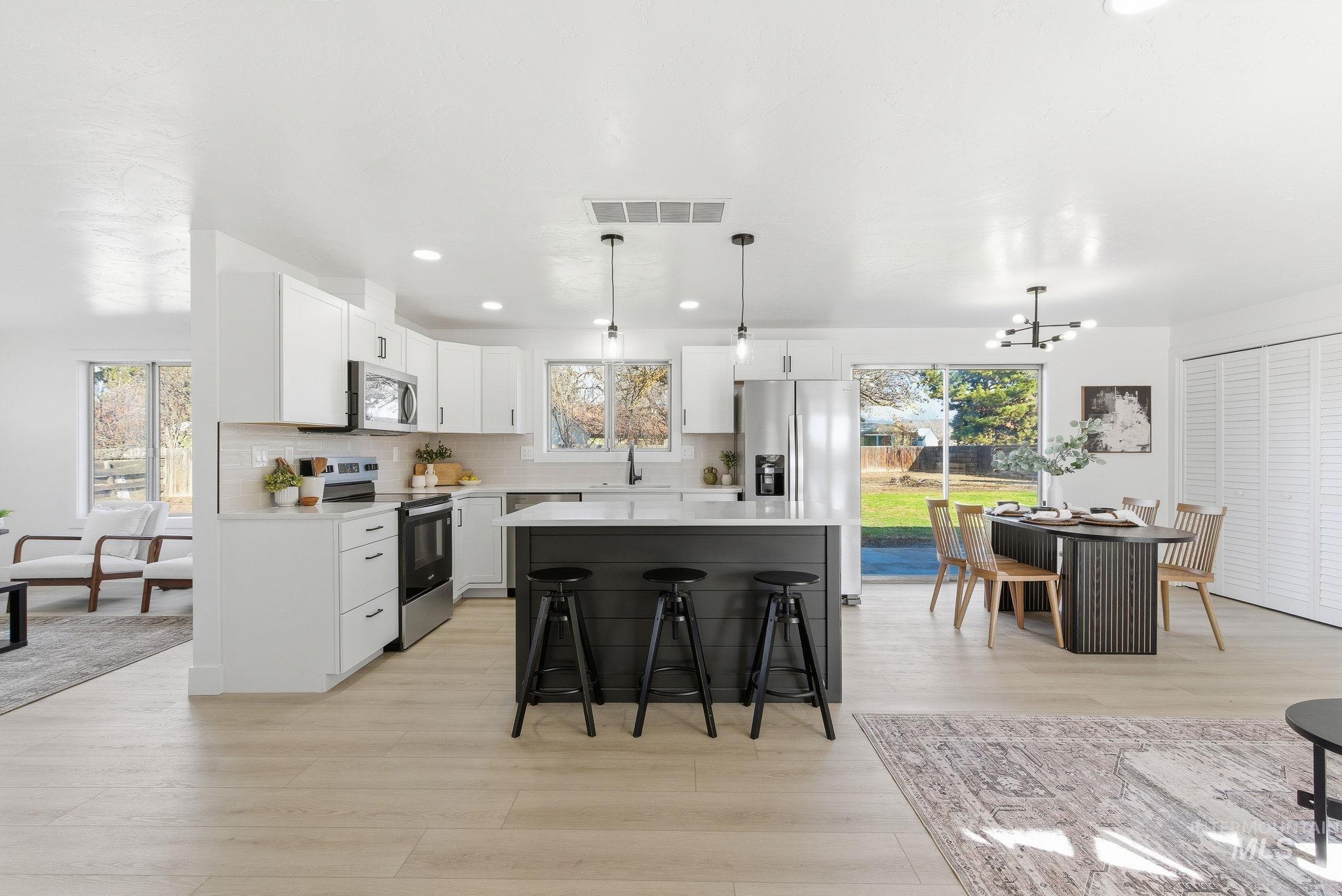 Kitchen with a center island, a kitchen breakfast bar, pendant lighting, stainless steel appliances, and white cabinetry