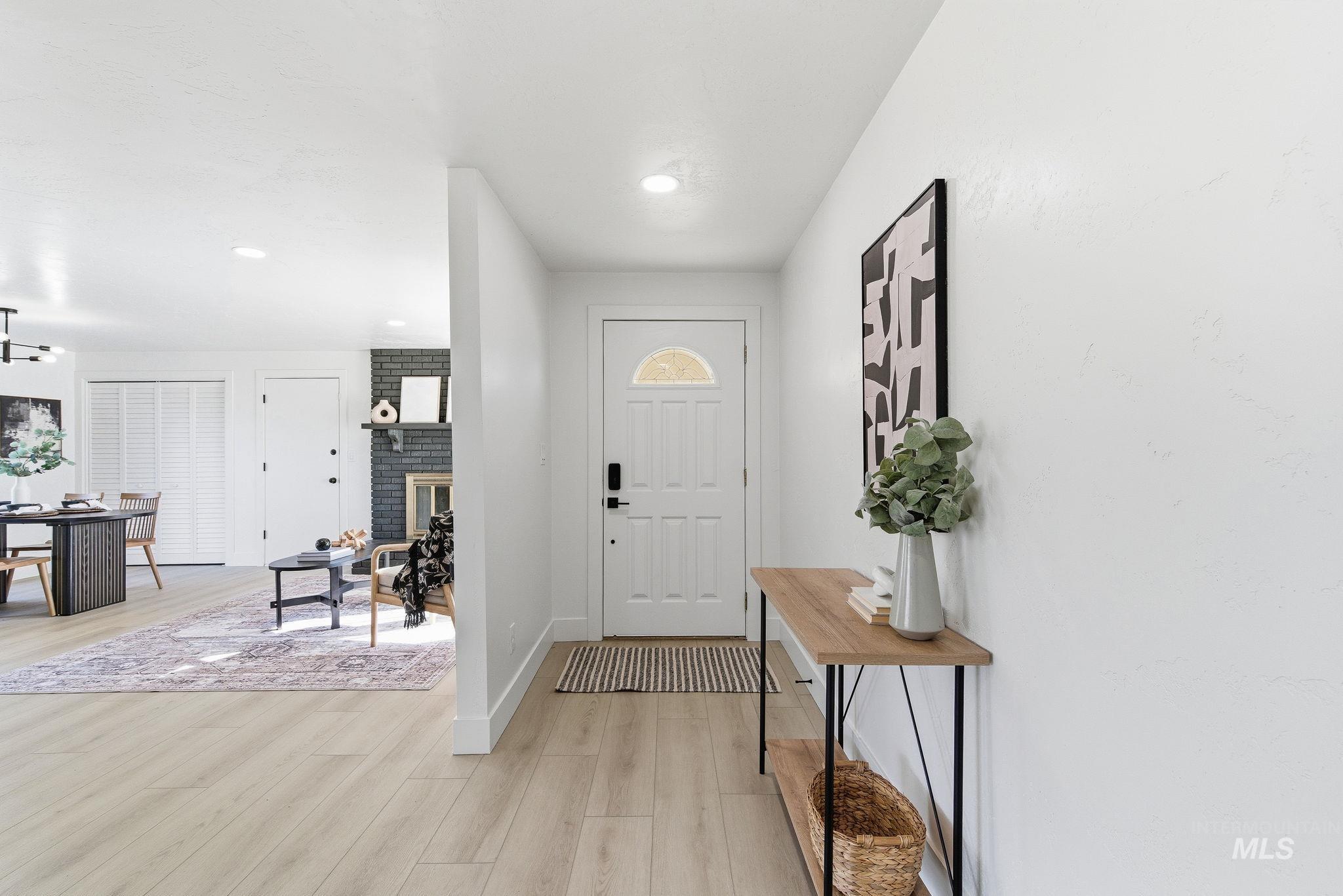 Entryway with light wood-type flooring, recessed lighting, and a brick fireplace