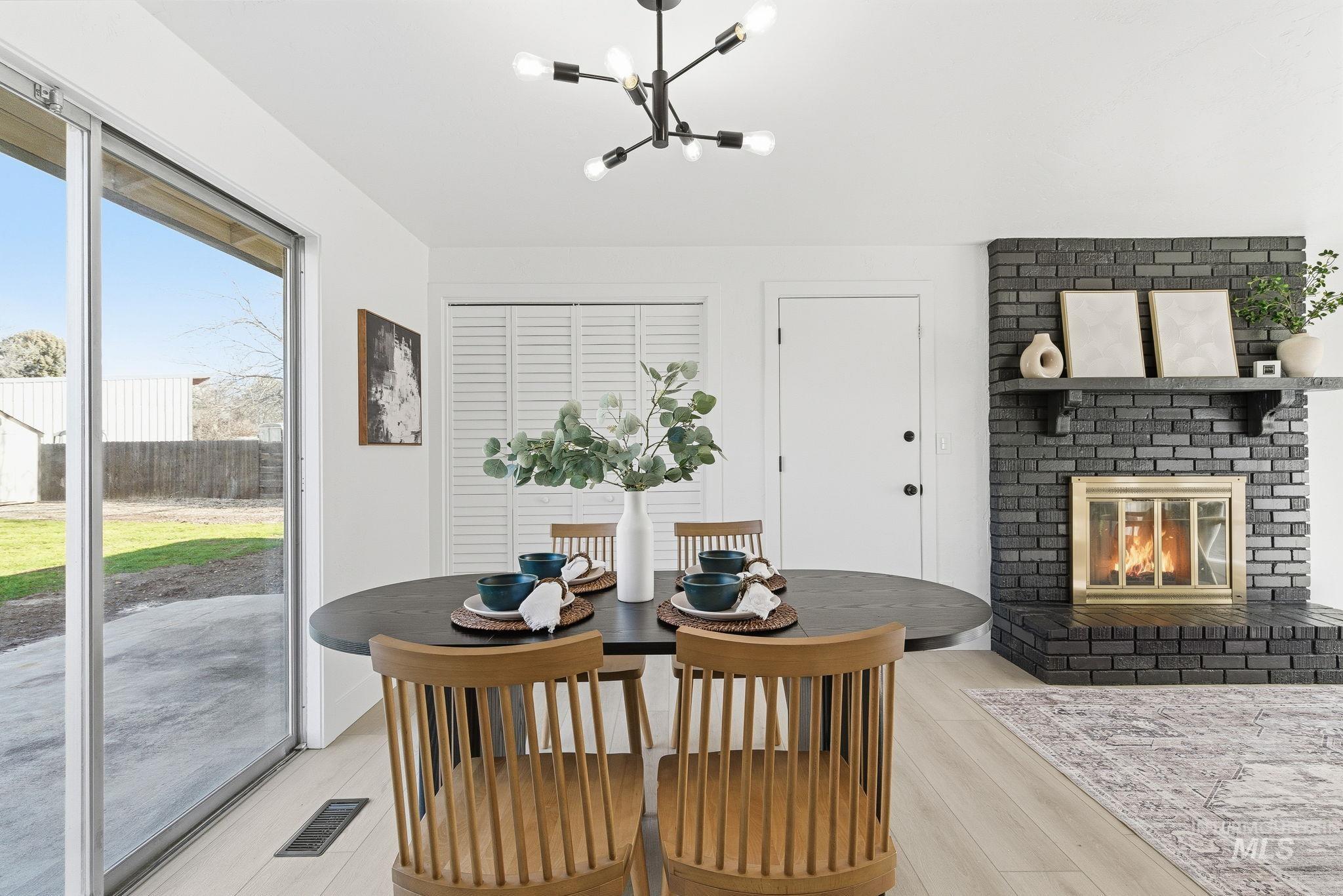 Dining area with light wood finished floors, a fireplace, and a chandelier