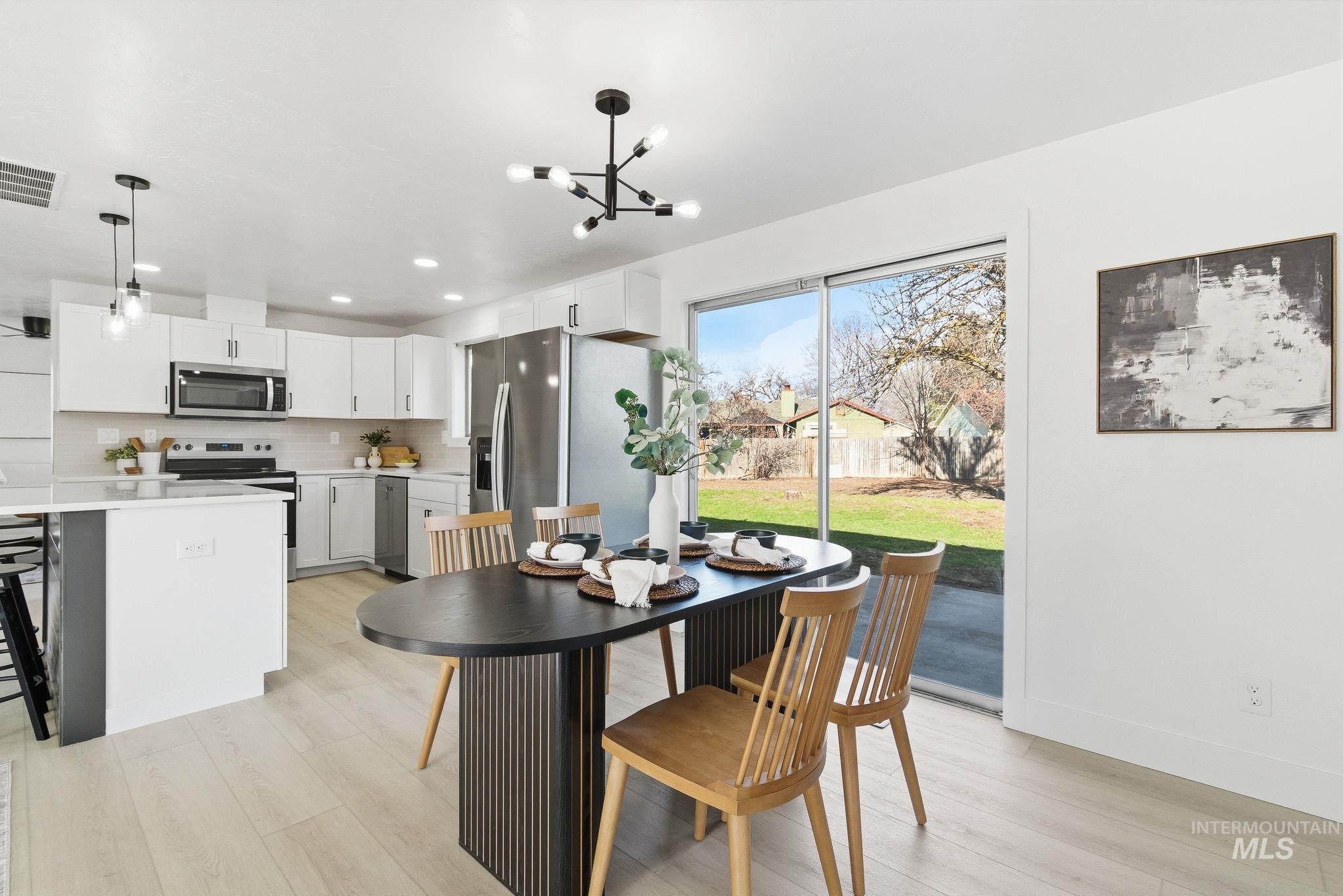 Dining area with light wood finished floors, a chandelier, and recessed lighting