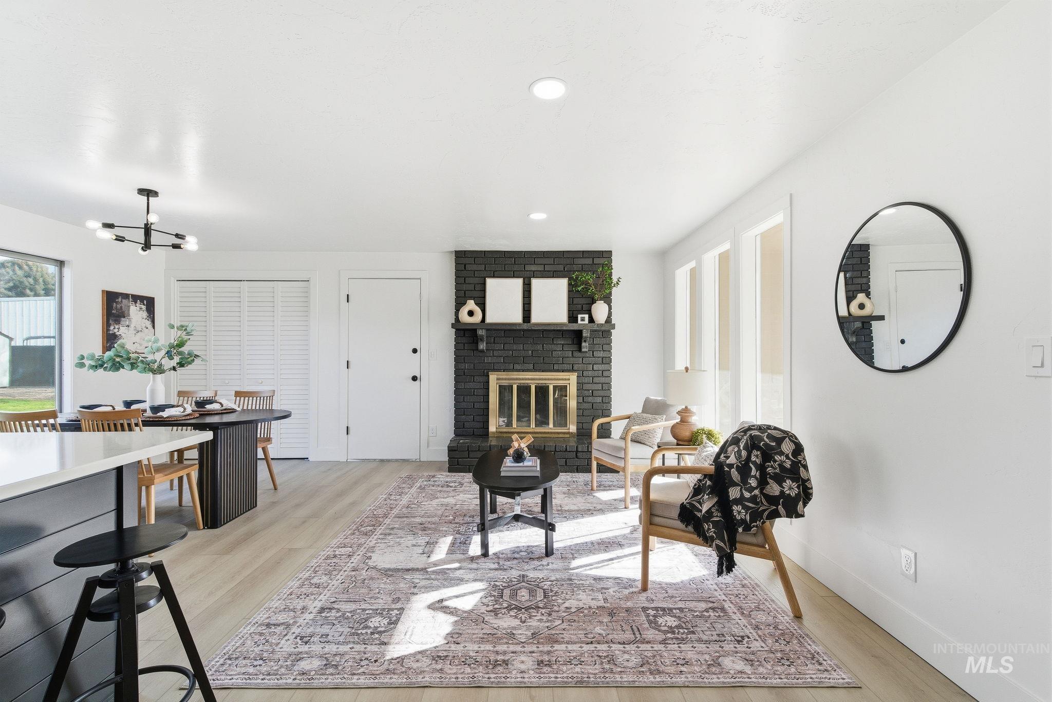 Living room with a fireplace, light wood finished floors, a chandelier, and recessed lighting