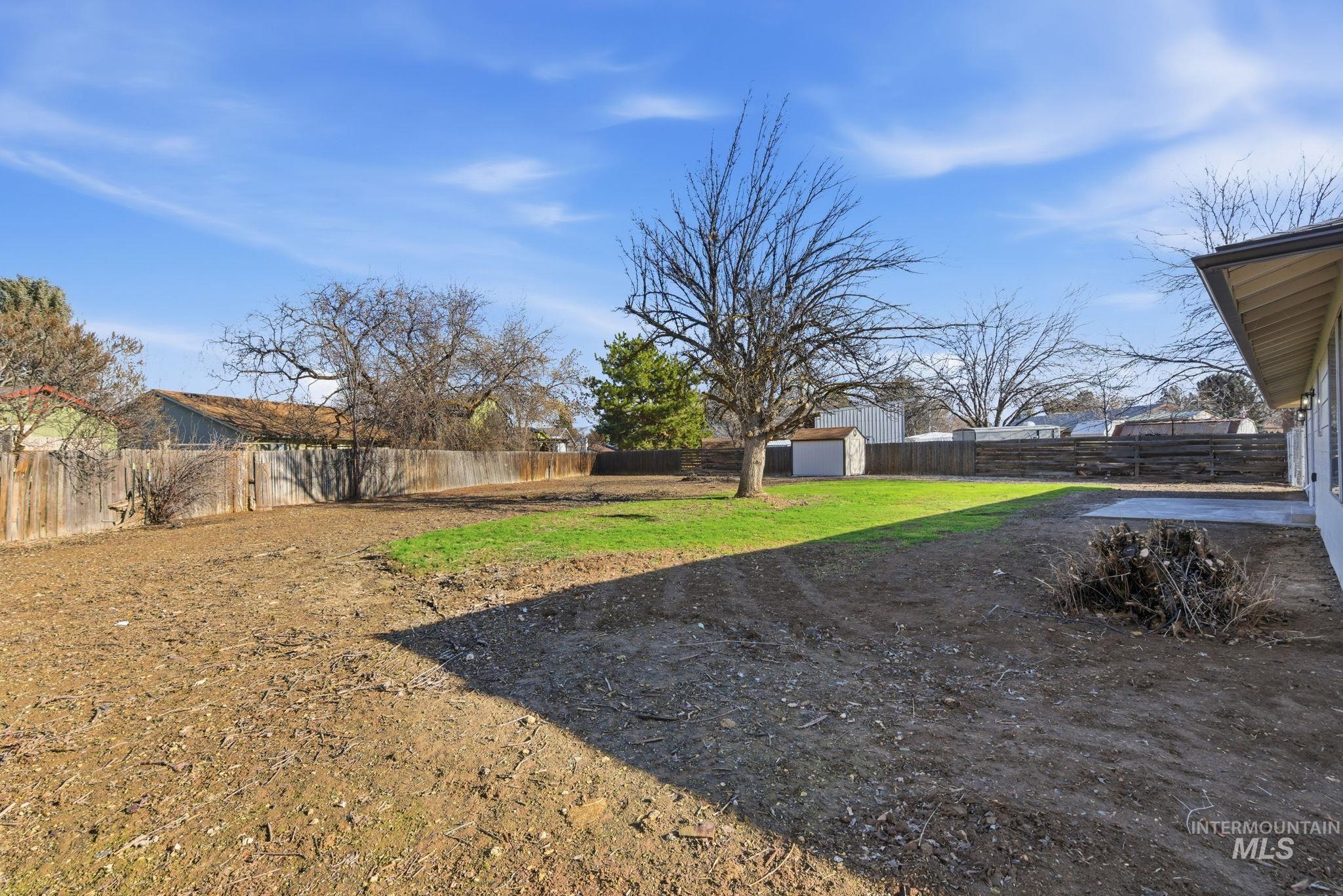 Fenced backyard featuring an outbuilding and a patio